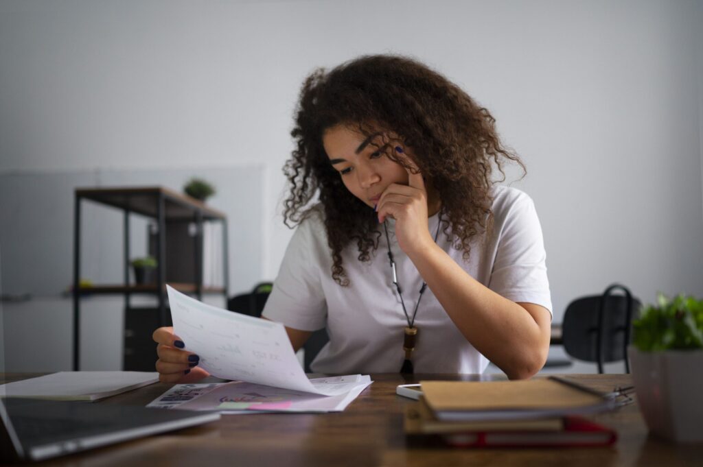 Estudante sentada em uma mesa lendo documentos.