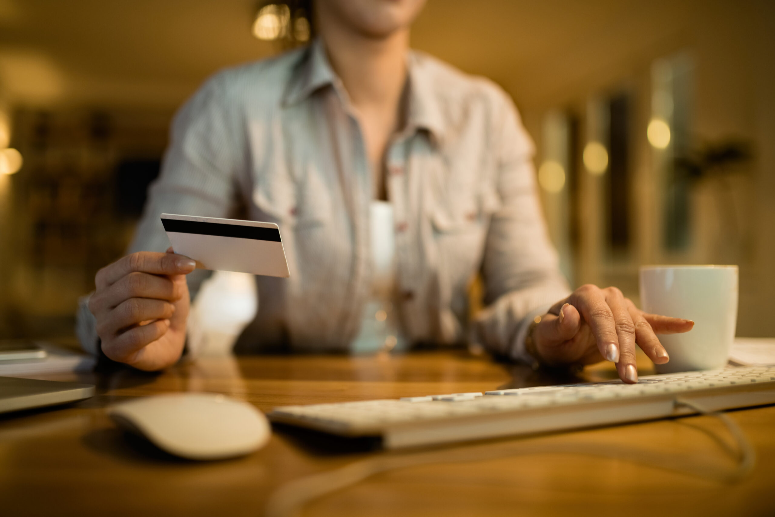Mulher usando computador e cartão de crédito para pagar suas dividas estudantis